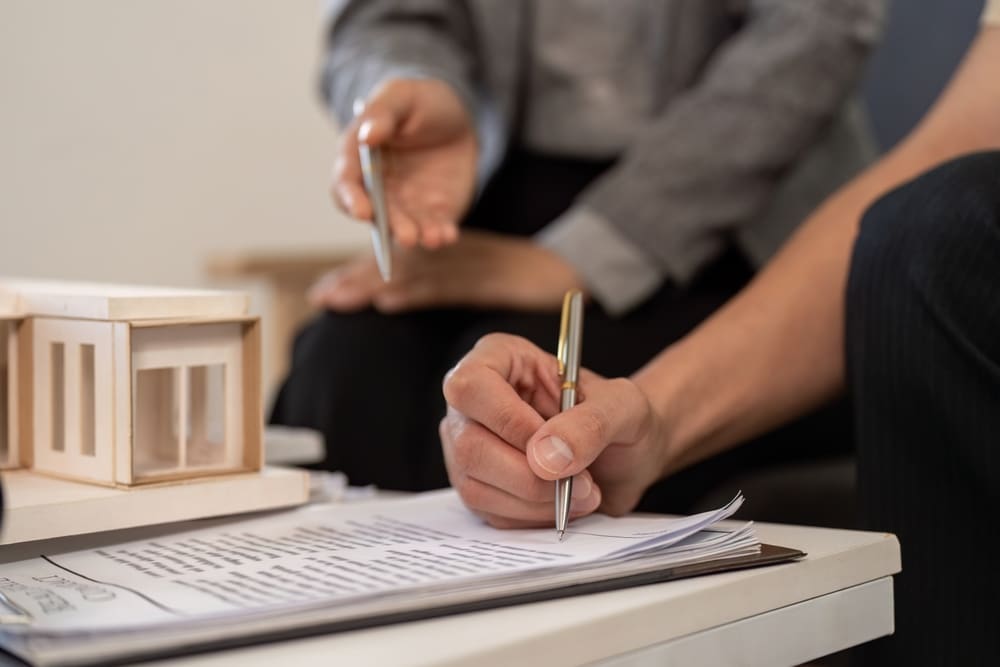Real,Estate,Agent,Assisting,Client,With,Paperwork,And,Model,Home